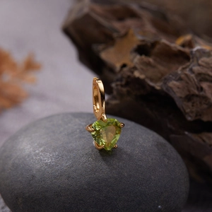 Detailed close-up of a gold-plated earring featuring a heart-shaped green gemstone