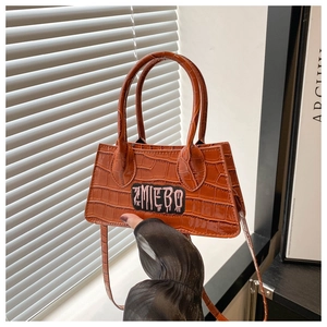 Detail of orange crocodile pattern mini handbag featuring ZMIEBO embroidery and top handle