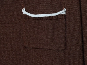 Macro detail of the dark brown knit fabric showing the pocket seam and contrast piping