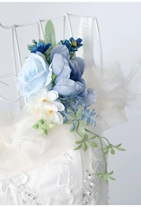 Close-up of blue rose and daisy corsage attached to a white lace wedding gown