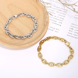Minimalist stainless steel pig nose buckle bracelet in silver and gold on wooden tray