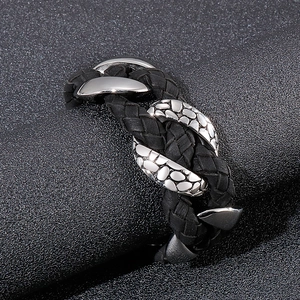 Close-up of men's leather braid bracelet showing textured metal scales and polished finish