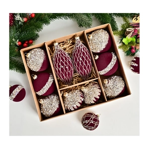 Macro detail of wine red flocked Christmas ornaments with glitter patterns in a kraft box