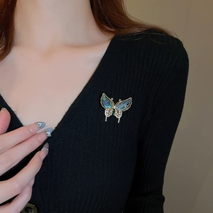 Détail d'une broche papillon en plaqué or avec nacre bleue et verte et zircons brillants