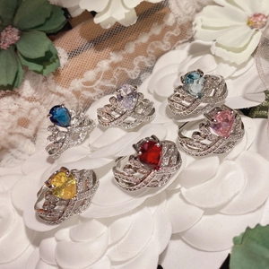 Detail of colorful pear-cut gemstone rings on white petals with 18K gold plated silver bands