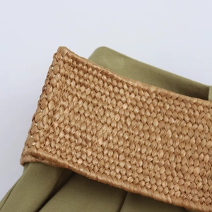 Close-up detail of the woven straw texture and green fabric lining of the casual shorts belt