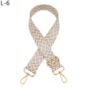 Dettaglio di tracolla regolabile beige con motivi geometrici e fibbie in metallo dorato