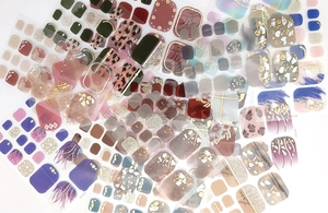 Flat lay of multiple waterproof toe nail stickers with floral, marble, and gold foil patterns