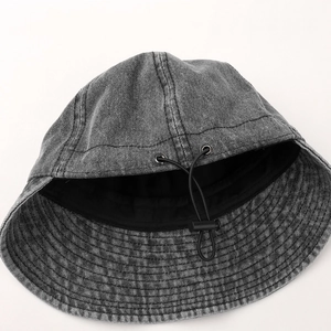 Detail of dark grey washed denim bucket hat with adjustable drawstring and metal eyelets