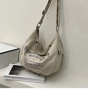 Détail d'un sac cabas en toile beige avec bandoulière réglable et poche latérale à pression