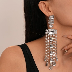 Gros plan de boucles d'oreilles à longs pompons scintillants et cristaux rectangulaires
