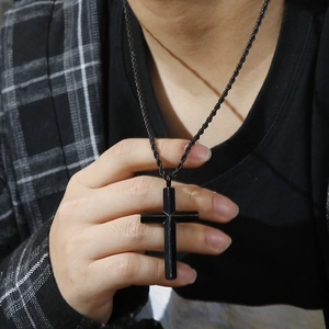 Detail of a black stainless steel cross pendant featuring a twisted rope chain on a model