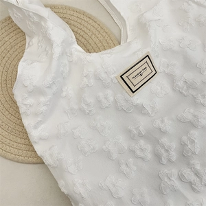 Close-up of white jacquard tote bag with 3D floral texture and Pleasant Time label