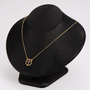 Gold stainless steel necklace with hollow circle cross pendant on black mannequin stand