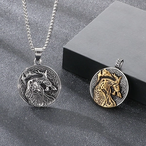 Detailed close-up of Viking wolf head pendants in silver and gold on a dark stone surface