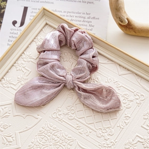 Pink velvet bow scrunchie on vintage embossed frame and newspaper background