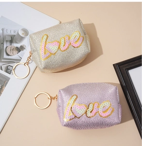 Close-up of glitter sequins LOVE embroidery on champagne and pink mini coin purses
