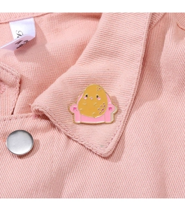 Détail d'un badge patate sur un col en jean rose montrant la texture fine de l'émail