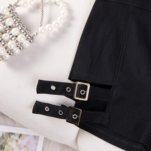 Dettaglio degli shorts neri a vita alta con fibbie decorative in metallo argentato laterali