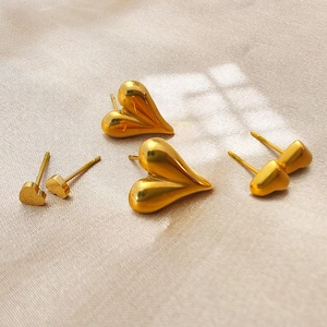 Trois tailles de boucles d'oreilles cœur en or poli et mat sur tissu de soie