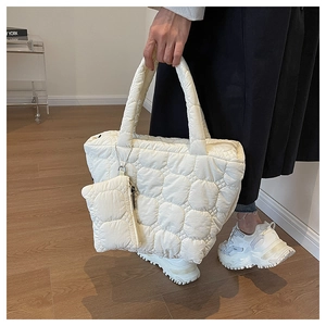 Detail of white quilted tote bag with wave stitching and matching small pouch accessory