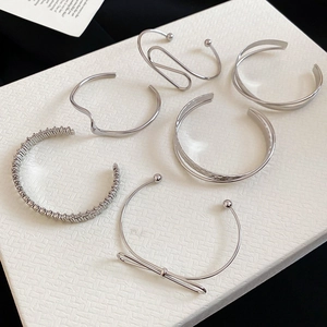 Macro shot of polished silver bangle set featuring various geometric and bow designs