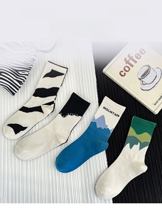 Detail of four crew socks featuring zebra stripes and mountain patterns on ribbed cotton fabric