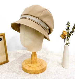 Detail of khaki cotton bucket hat with decorative button strap on a wooden model head