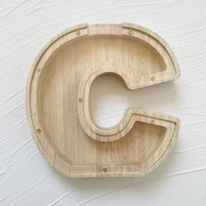 Detail of letter C shaped oak wood piggy bank with transparent acrylic front and screws