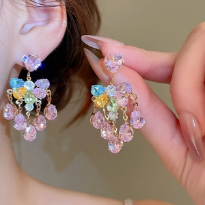 Detail of colorful waterdrop crystals hanging from a pink heart-shaped rhinestone earring