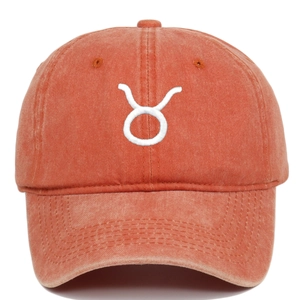 Detail of Taurus zodiac embroidery on washed cotton orange baseball cap surface