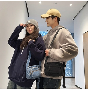 Couples wearing blue denim and black canvas mini crossbody bags with adjustable straps