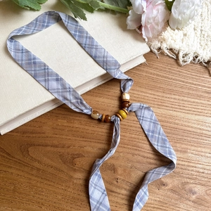 Macro detail of the plaid chiffon necklace featuring unique wood and acrylic bead accents