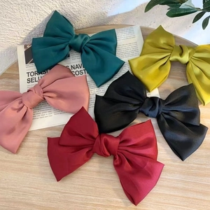 Elegant large satin bow hair clips in five colors on a rustic wooden surface