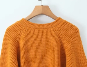 Détail du tricot épais et du col rond sur le pull en maille de couleur jaune gingembre