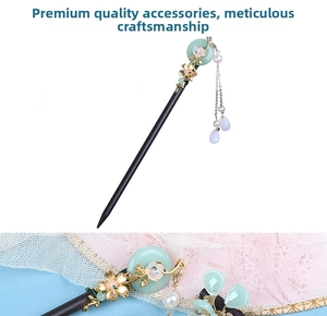 Close-up of wooden hair stick with jade-like bead, golden flowers and pearl tassels
