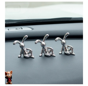 Detailansicht von drei versilberten Kaninchenfiguren als Auto Armaturenbrett Deko