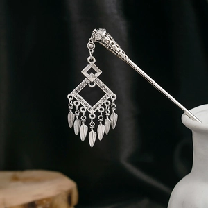 Detail of silver floral hair stick with geometric pendants and leaf tassels in a vase