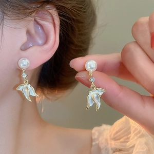 Détail de boucles d'oreilles perles avec strass et pendentifs en forme de pétales blancs