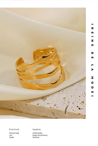 Détail d'une bague dorée ajustable avec texture ondulée sur soie beige et pierre