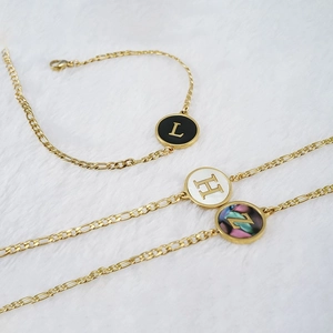 Bracelet doré en acier 18K avec breloques lettres rondes en nacre sur fond en fourrure