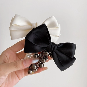 Detail of satin bow hair ties with elegant white pearls and glossy beads decoration