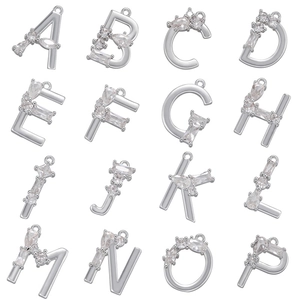 Macro detail of brass alphabet pendants A-P featuring micro-pave clear zircon inlays