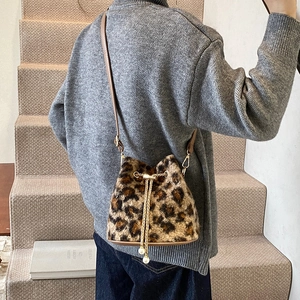 Leopard print plush bucket bag with metal chain strap worn by a model in a minimalist setting