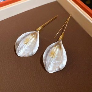 Détail des boucles d'oreilles pétales nacrés avec crochets dorés sur fond brun