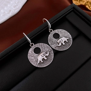 Gros plan détaillé de boucles d'oreilles éléphant rétro avec relief soleil bohème