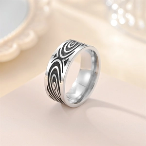 Detailed view of silver titanium steel ring featuring black abstract swirl carvings