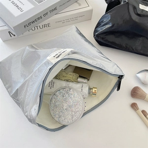 Internal view of silver metallic makeup bag showing large capacity and soft fabric lining