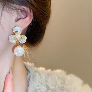 Detailed close-up of large pearl flower earrings with gold plating on a model