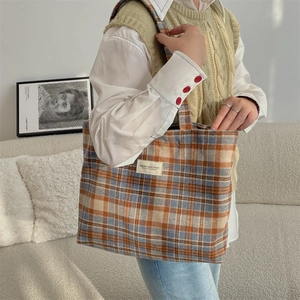 Detail of vintage plaid canvas tote bag featuring premium woven fabric and brand label